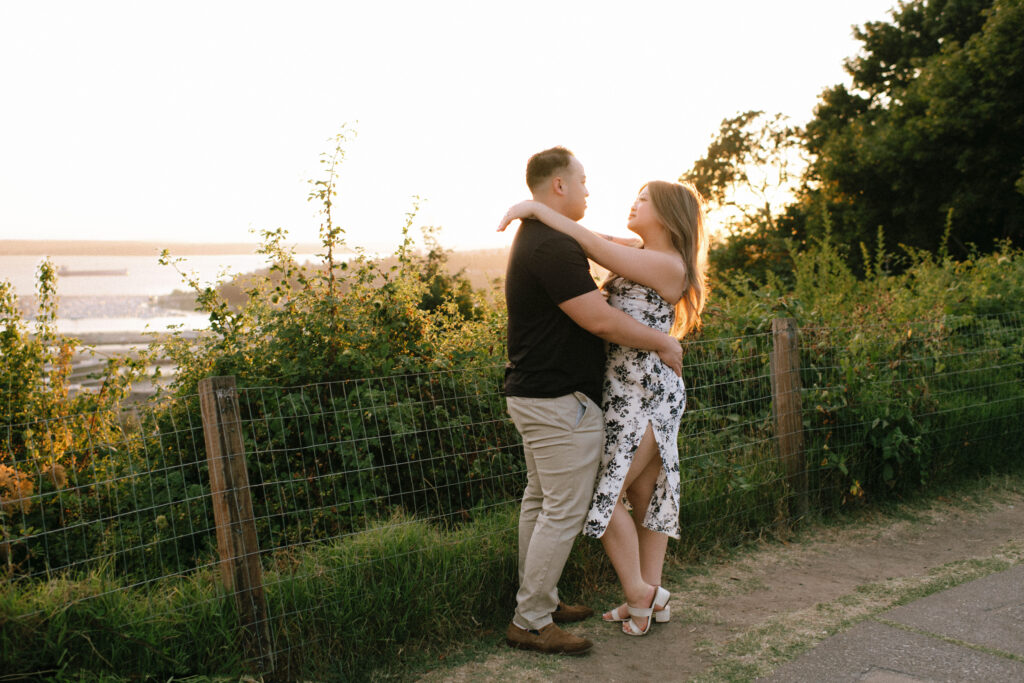 Yue and Ka embrace during their surprise proposal at Kerry Park in Seattle, captured by Rachael Marie Photography at sunset overlooking the city.