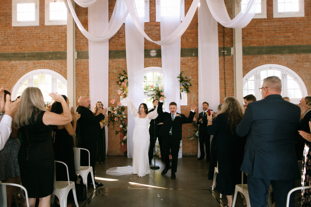 Bride and groom celebrating as they walk back up the aisle after their ceremony at BRICK in San Diego