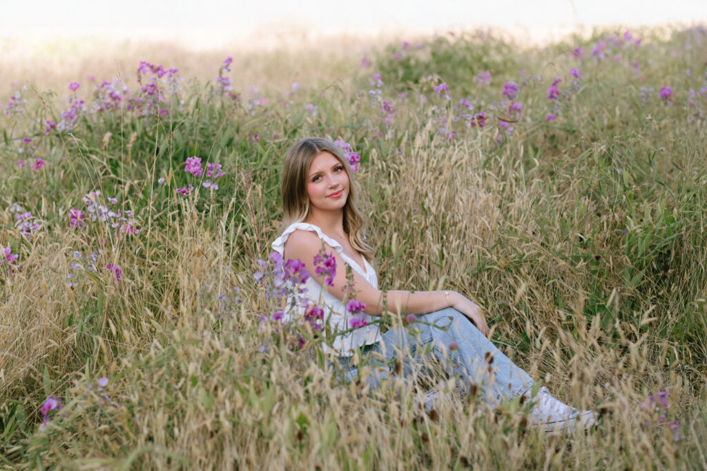 Woodinville high school senior sitting in a wildflower field at sunset during a natural light senior session in Washington
