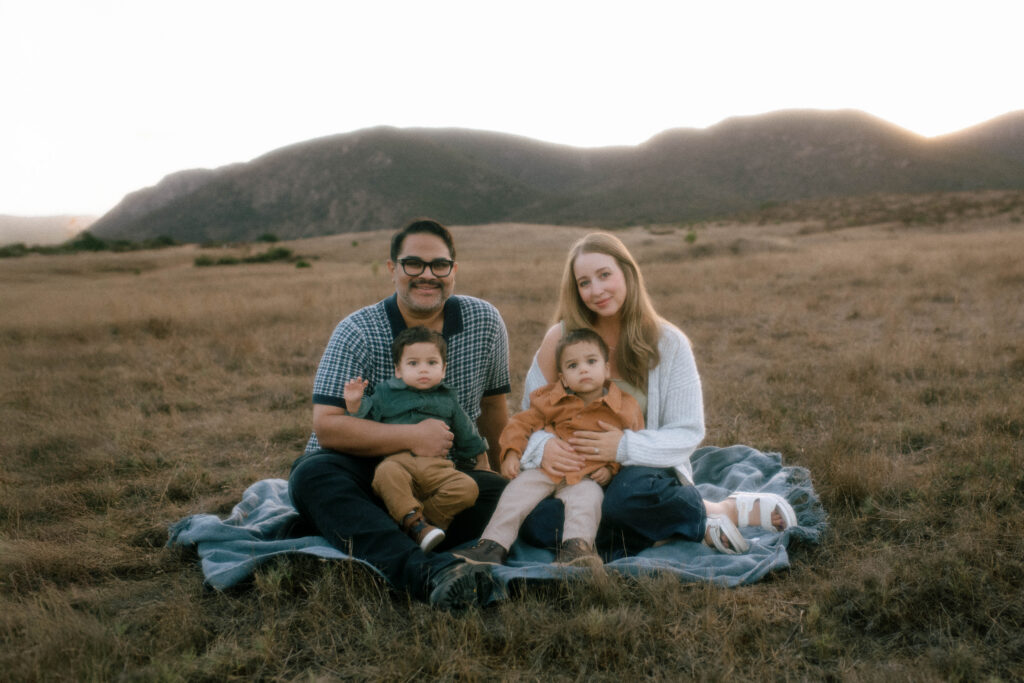 Navamani family sitting together on a blanket at Mission Trails Regional Park during golden hour in San Diego