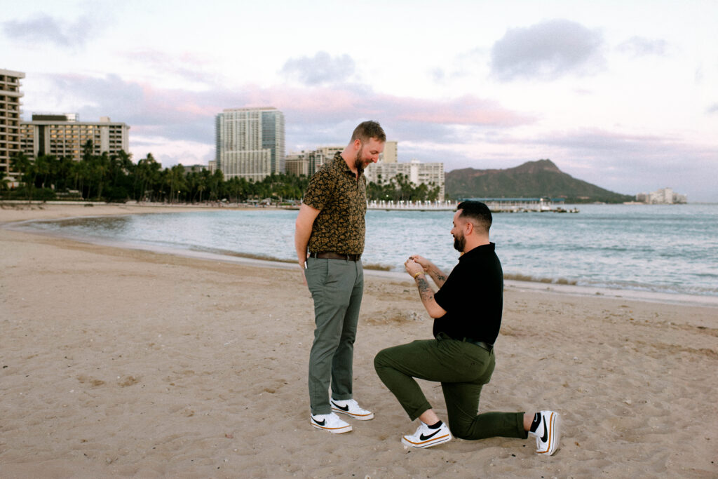Michael’s surprise proposal to Garrett on Waikiki Beach at sunset with loved ones witnessing the moment