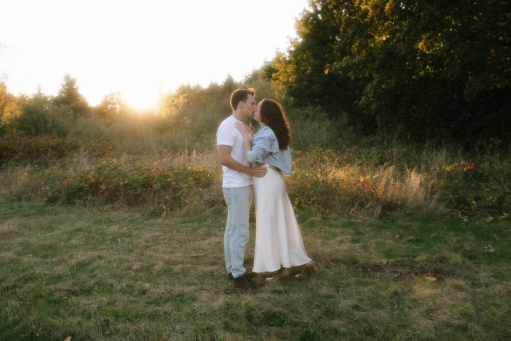 Couple embracing in golden evening light at Discovery Park engagement session in Seattle, Washington — Rachael Marie Photography
