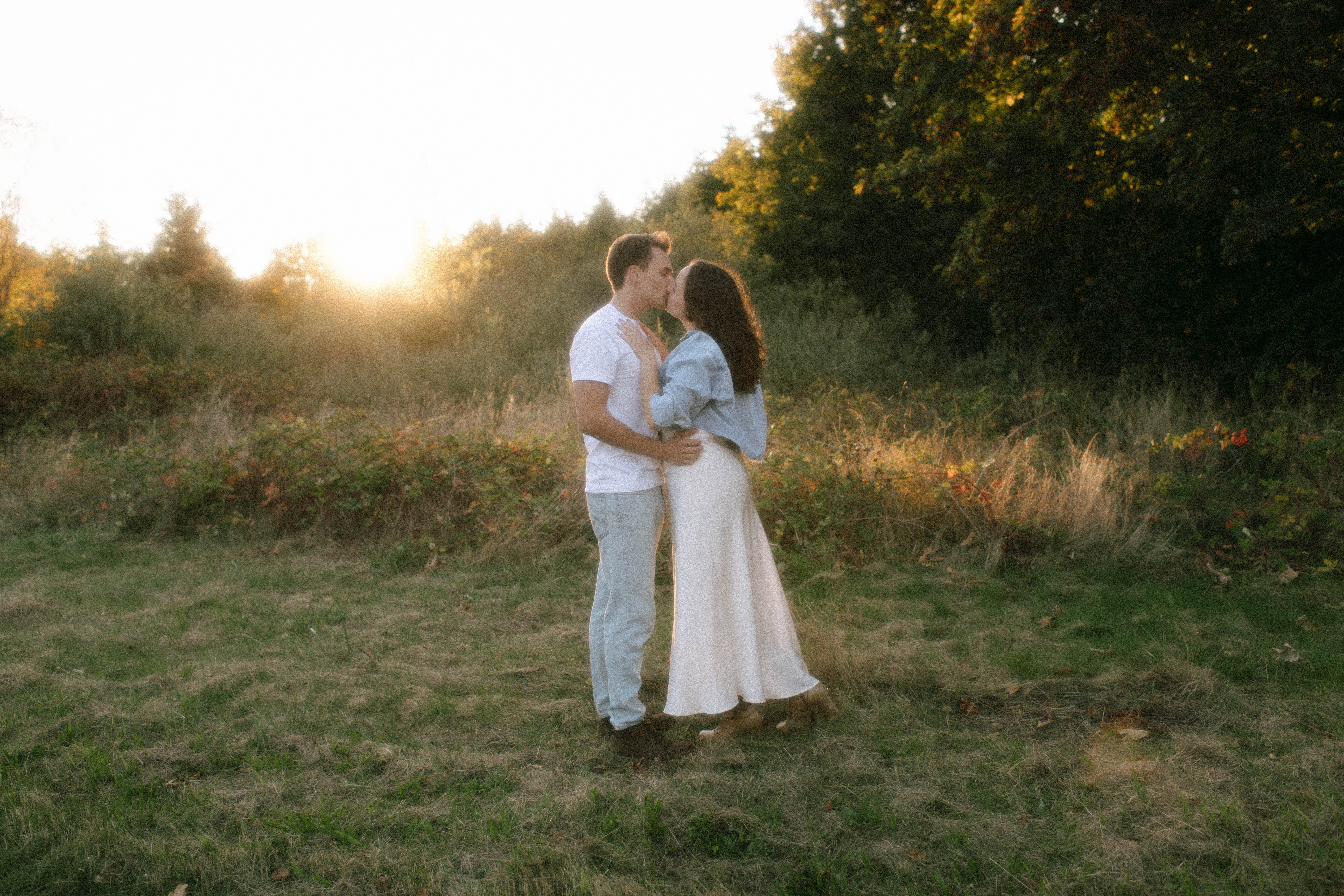 Couple embracing in golden evening light at Discovery Park engagement session in Seattle, Washington — Rachael Marie Photography